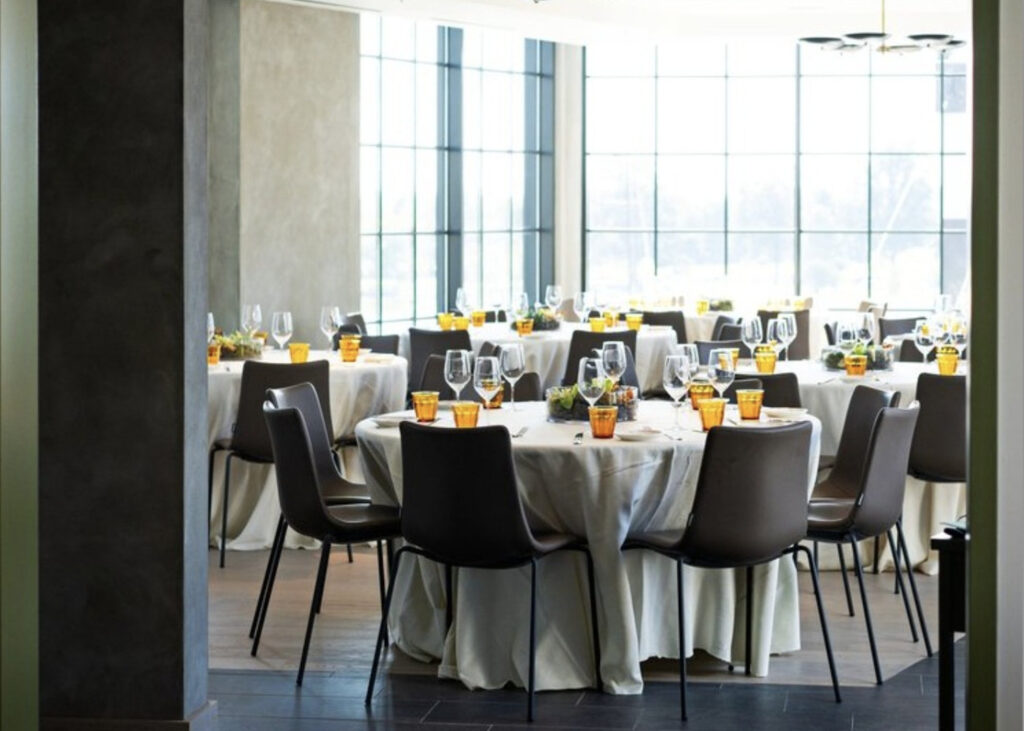 Officina dining room with cream linen tablecloths and bright yellow glassware