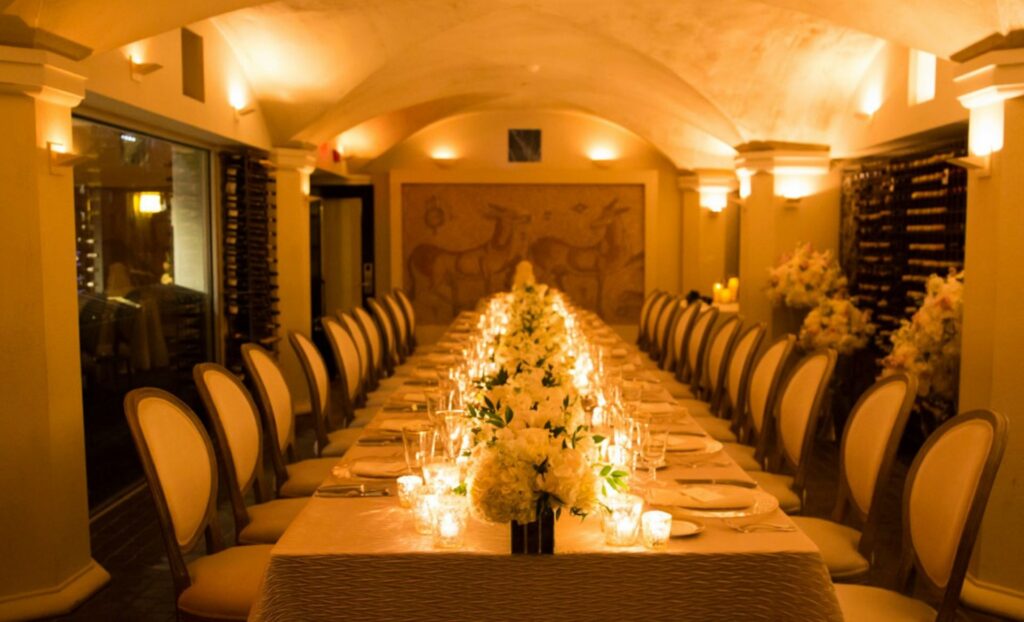 Private dining space at Mooo restaurant in Boston. A table lined with votive lights and flower arrangements.