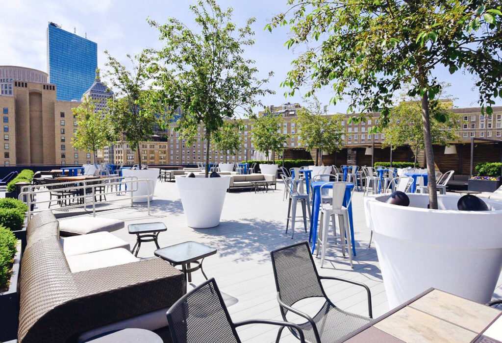The rooftop at Revere Boston Common with many lounge areas, high tops, and large potted trees