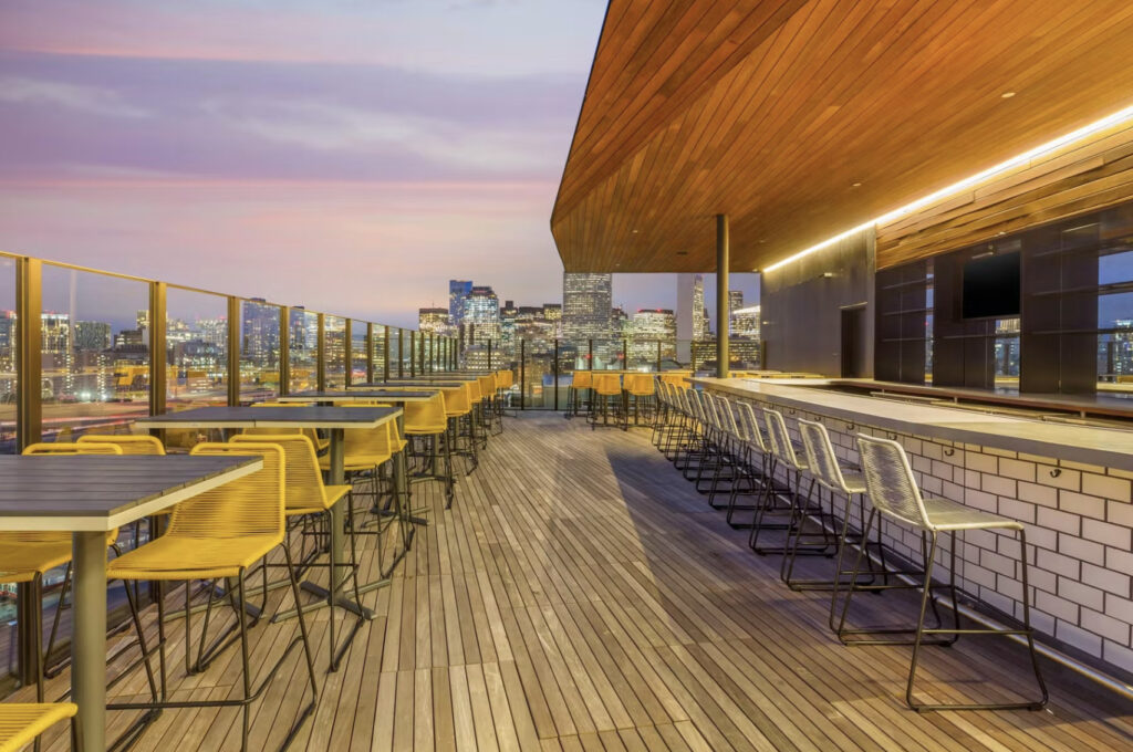 Six\West Rooftop in boston with a long bar and views of Boston at sundown