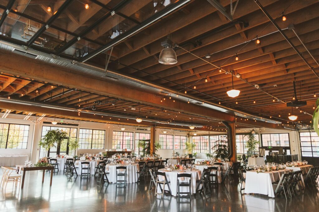 Large space with dining tables with white table cloth and wooden panel ceilings