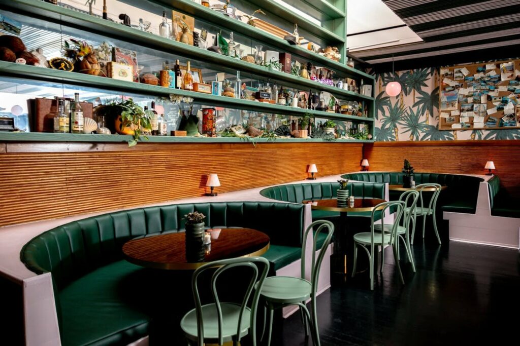 The Happiest Hour in NYC with green lounge booths and tropical wallpaper 