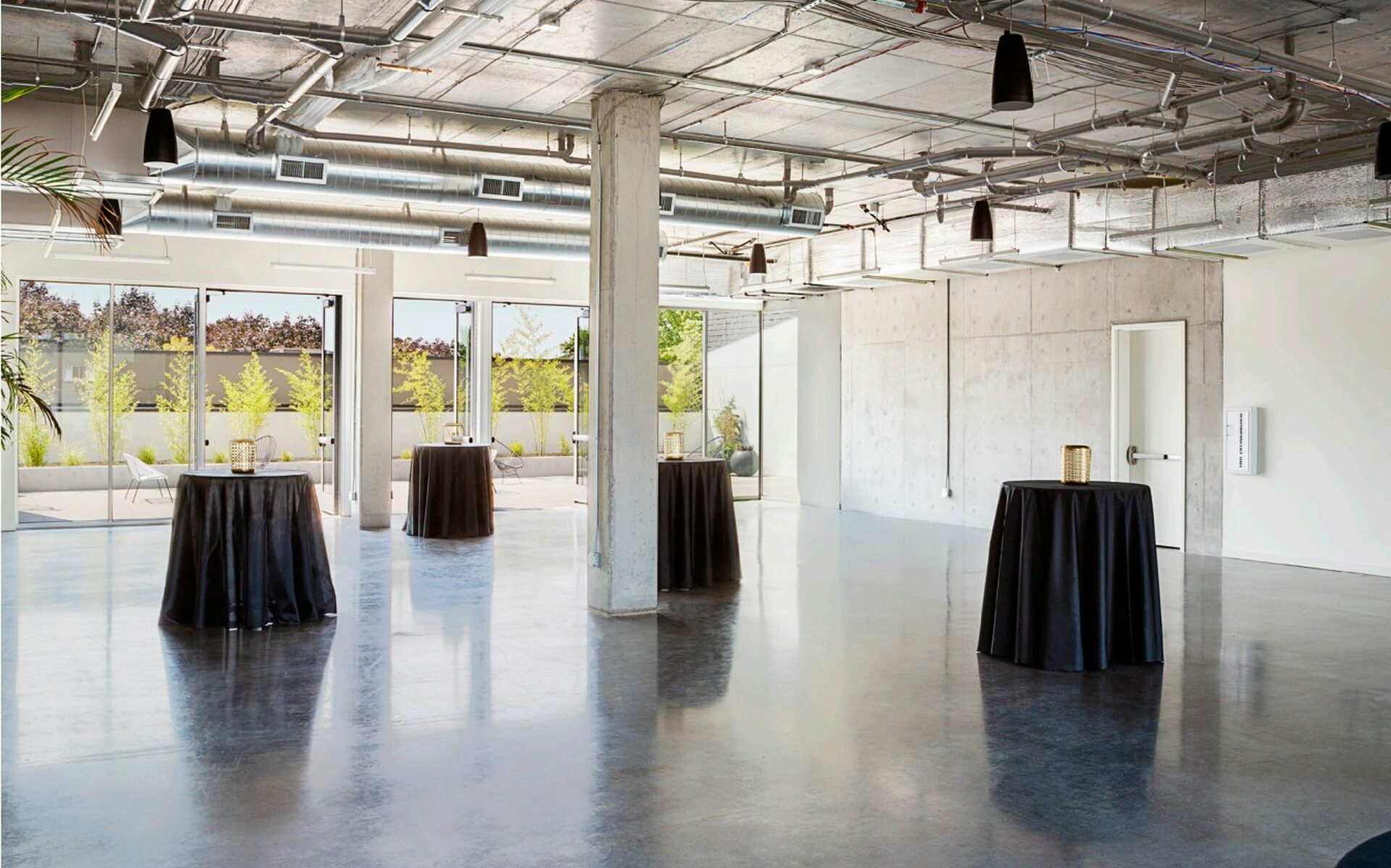 Event space with windows and small tables with black table cloths