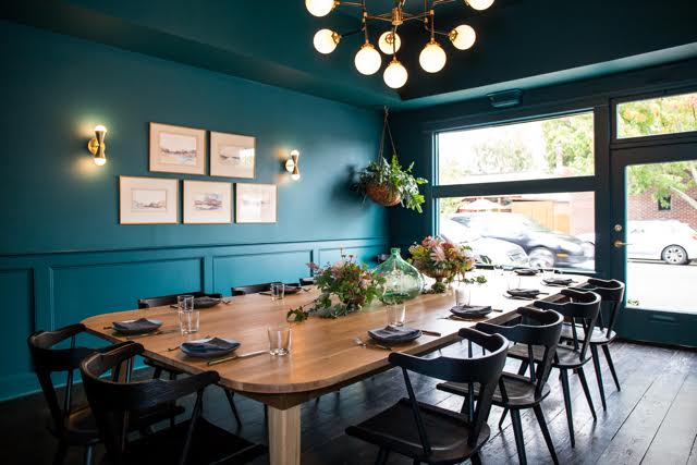 private dining room with teal colored walls and wooden dining table