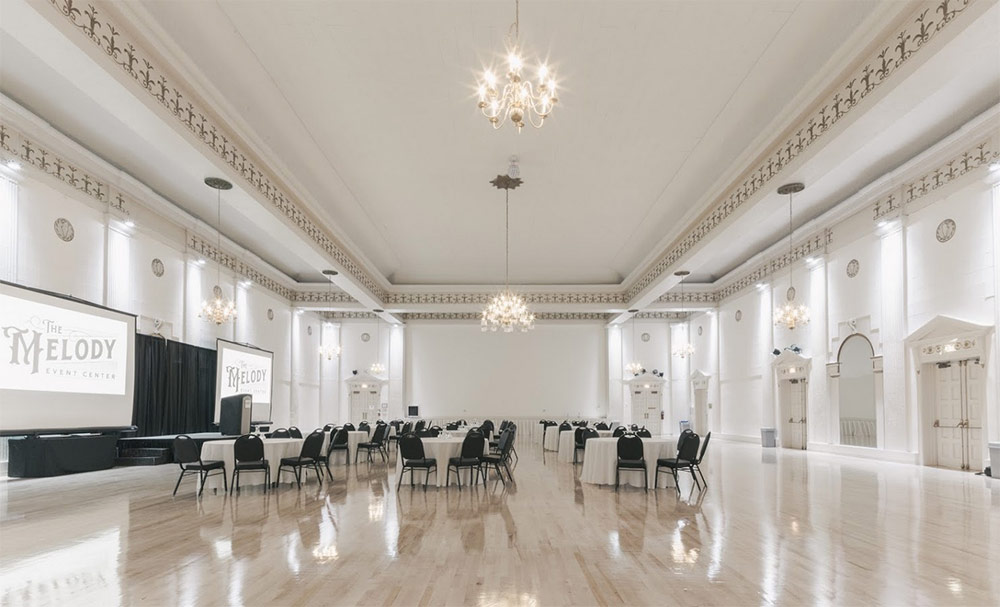 Large white venue and ballroom space with chandeliers