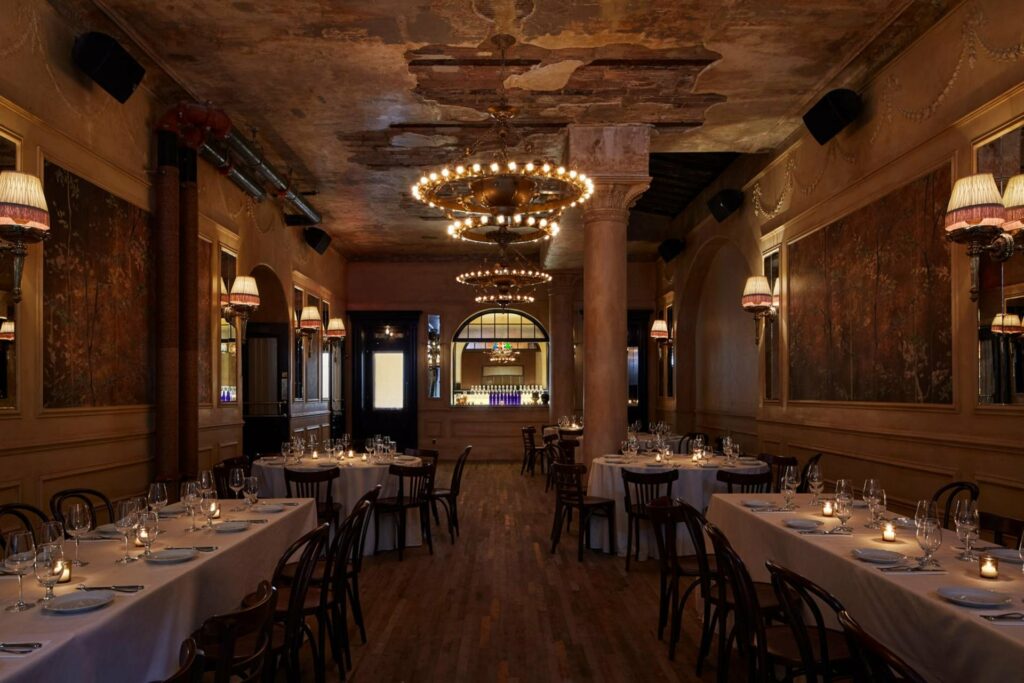 The dining room of The Hotel Chelsea with low lighting and white table cloths.