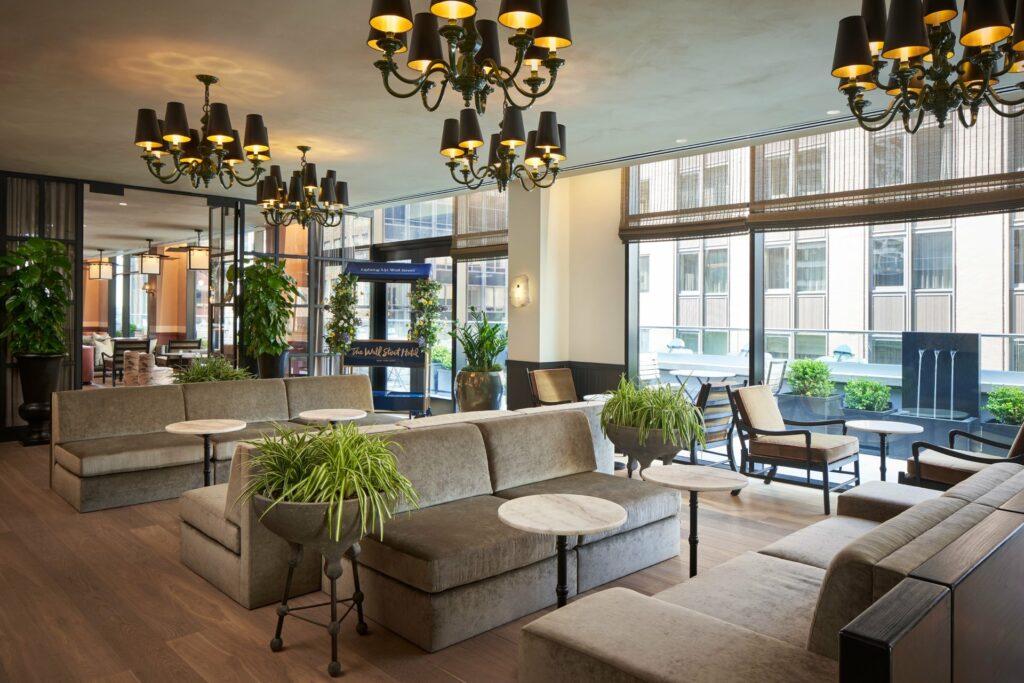 Bright meeting space of The Wall Street Hotel with grey couches and plants