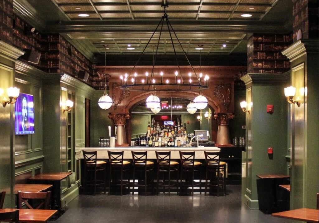 Stout at Penn Station in NYC with green walls and a large arched bar