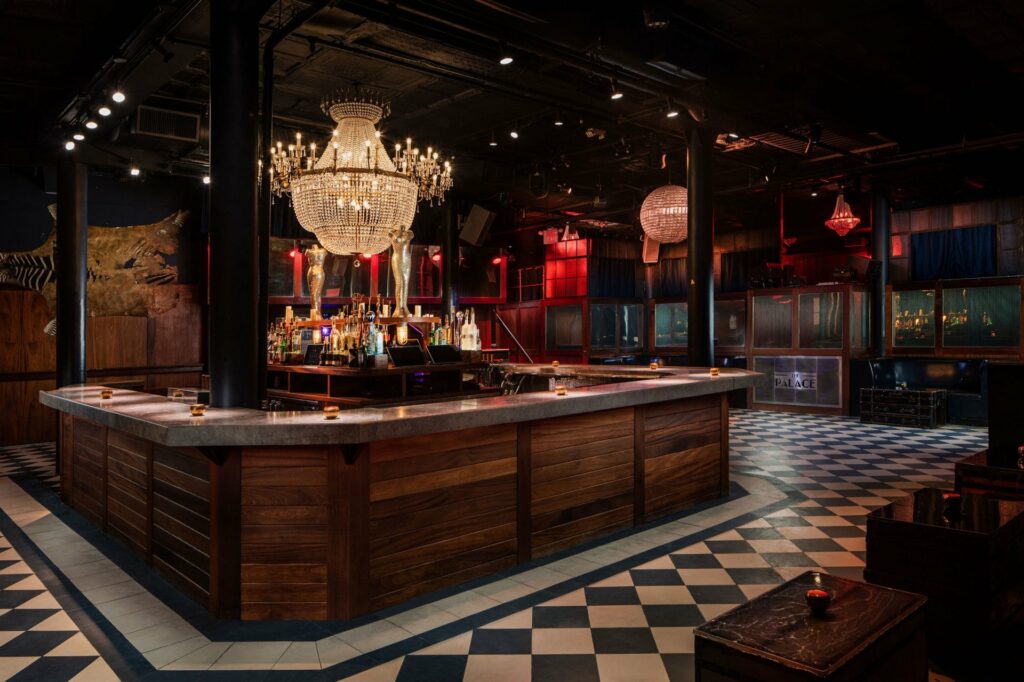 Bar with checkered floor and large chandelier at The Palace NYC