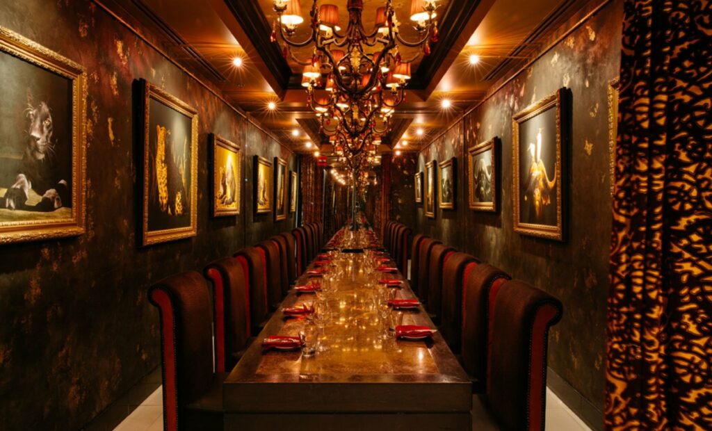 A long private dining room in Orlando table with red chairs and chandeliers

