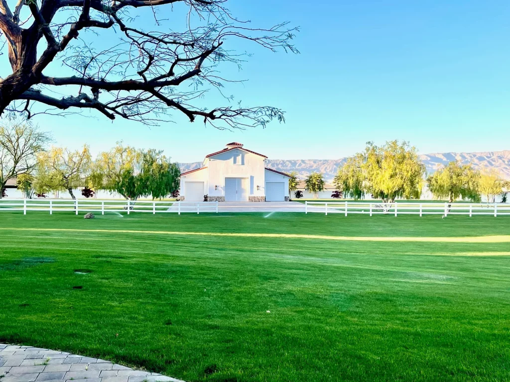 A large ranch with a white house and fence at a  Coachella event venue
