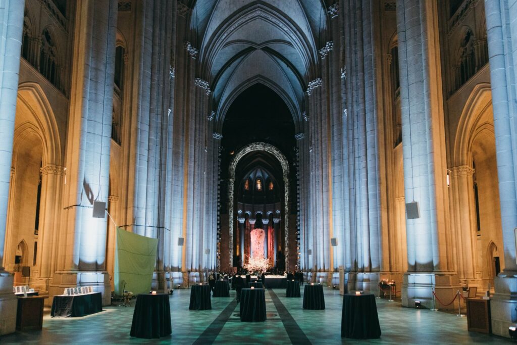 Cathedral space with black linen tables and uplighting 