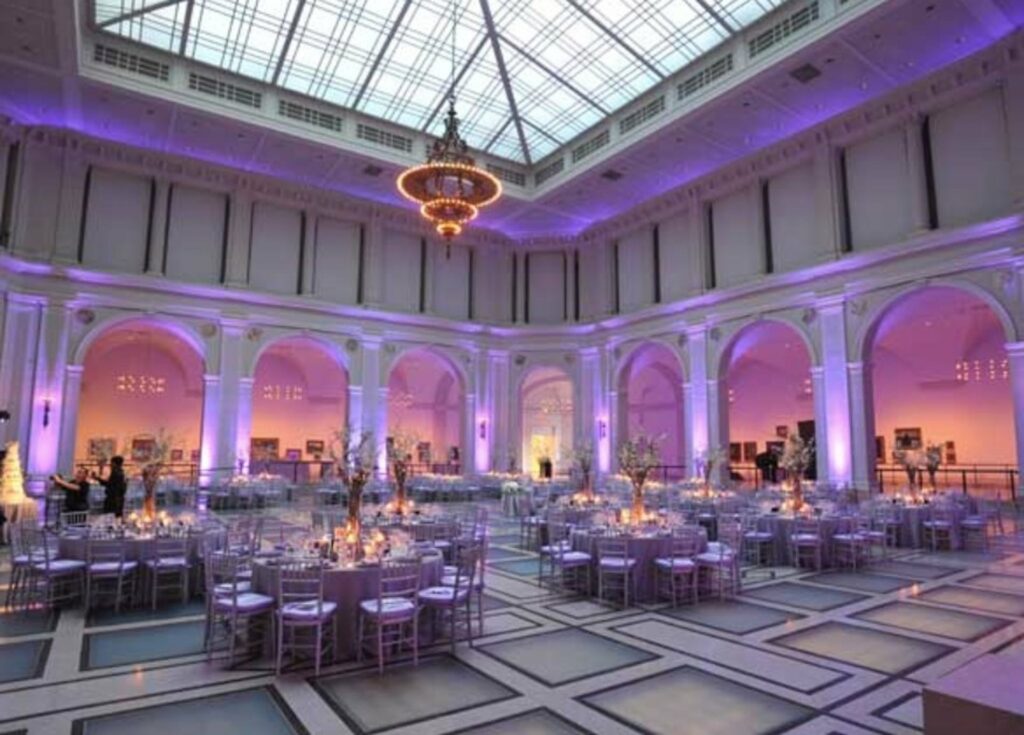 White event hall with skylight ceiling with purple lighting and white banquet furniture