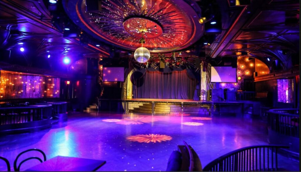 large dance floor with disco ball and stage with colorful lighting