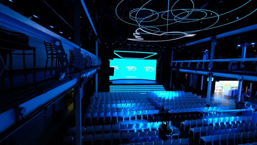 LED backdrop stage with rows of white chairs and blue lighting set up for a conferene