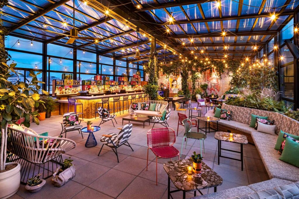 Rooftop bar with glass ceiling and walls and eclectic colorful furniture
