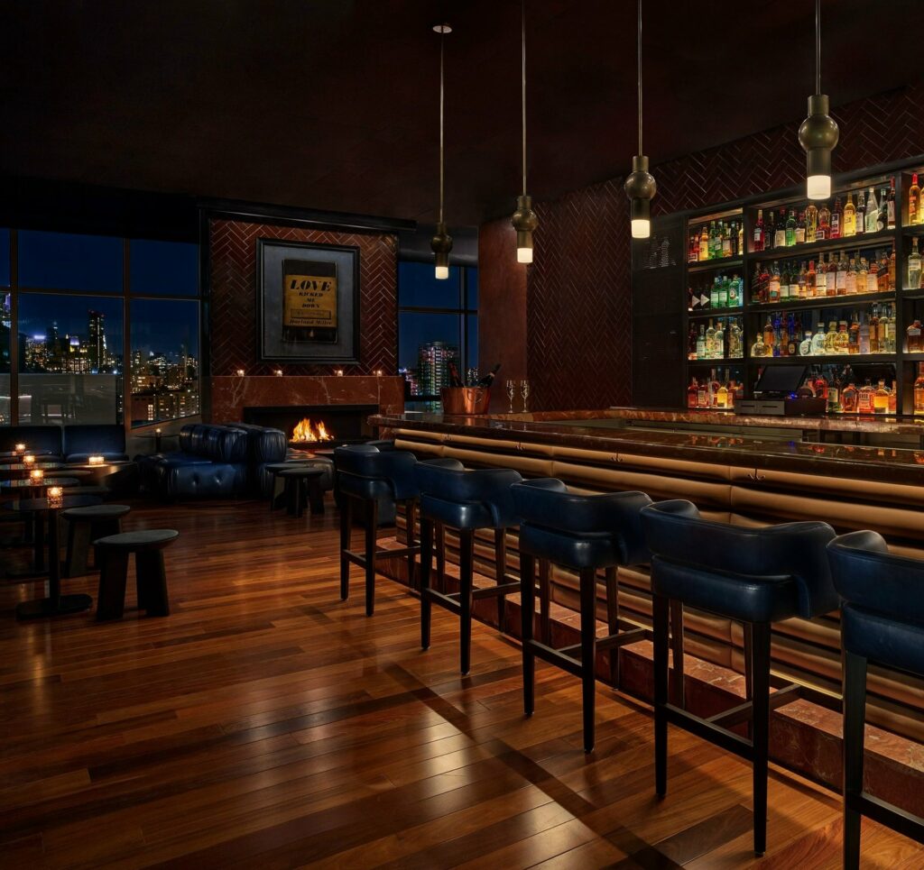 Luxurious bar with wood floors and leather stools and illuminated bottles