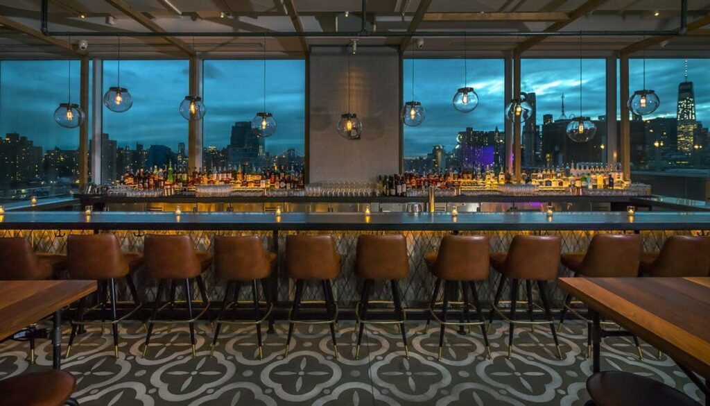 Rooftop bar overlooking the city with tiled floor and leather stools and sphere pendant lights