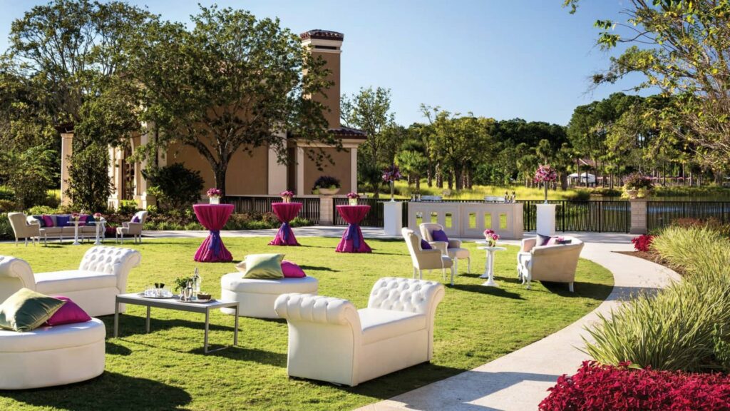 Four Seasons Resort Orlando at Walt Disney World Resort open lawn space and garden with white lounge furniture and purple high cocktail tables