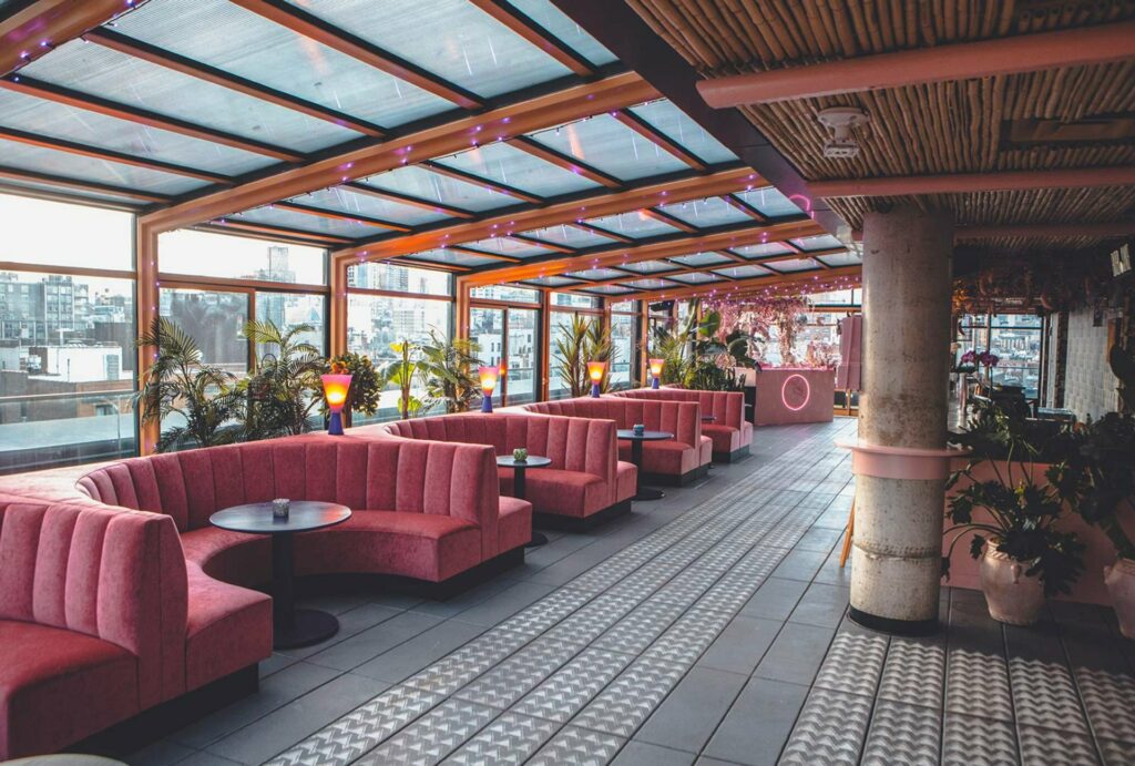 Rooftop bar with glass and bamboo roof and pink banquettes