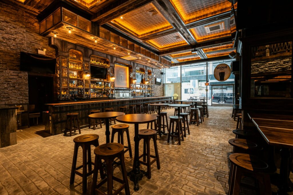 Irish bar with cobble stone floor and wooden bar stools and illuminated bar