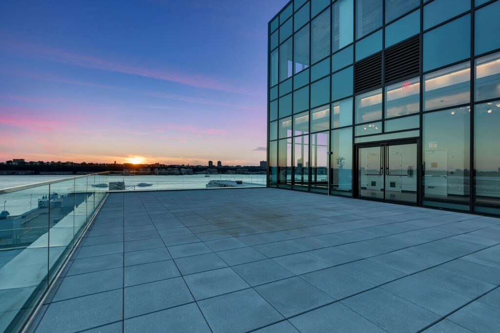 Glass building with large terrace overlooking the sunset and water