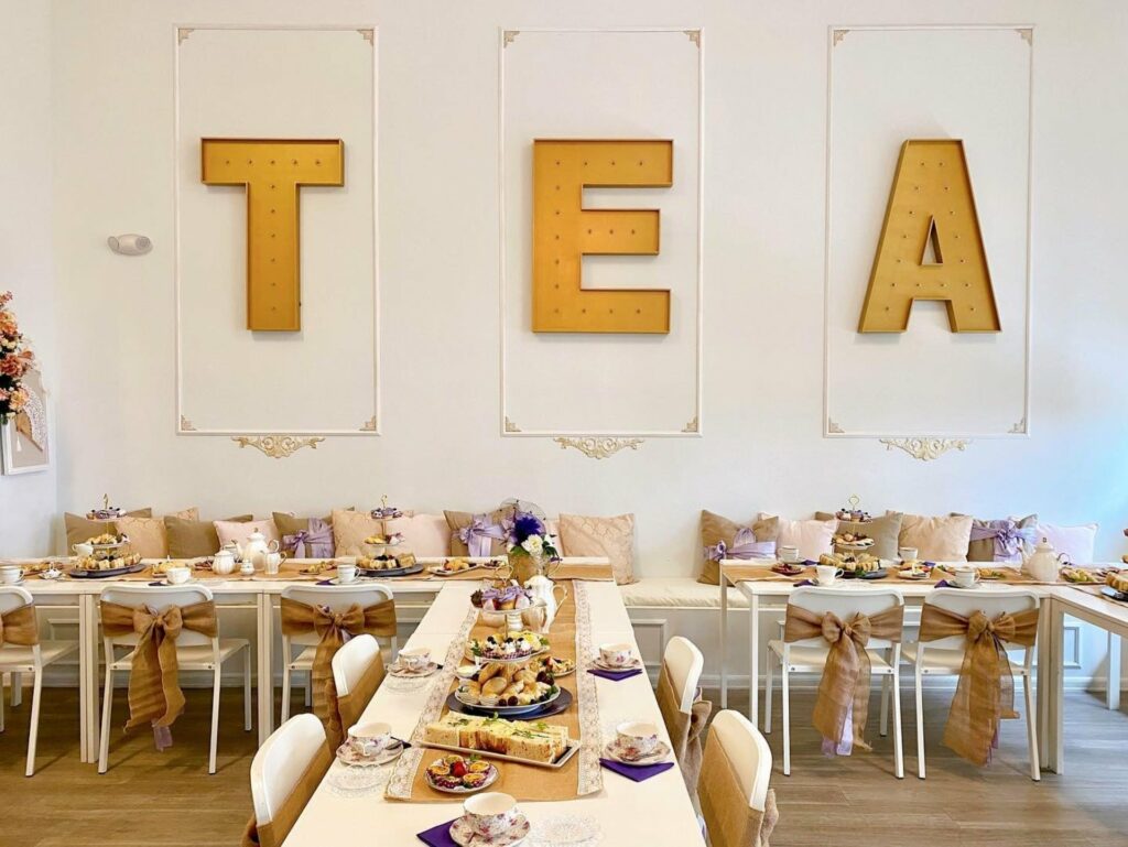 private dining room in Orlando with tables and chairs and a table with food and sign that reads "TEA" on the wall
