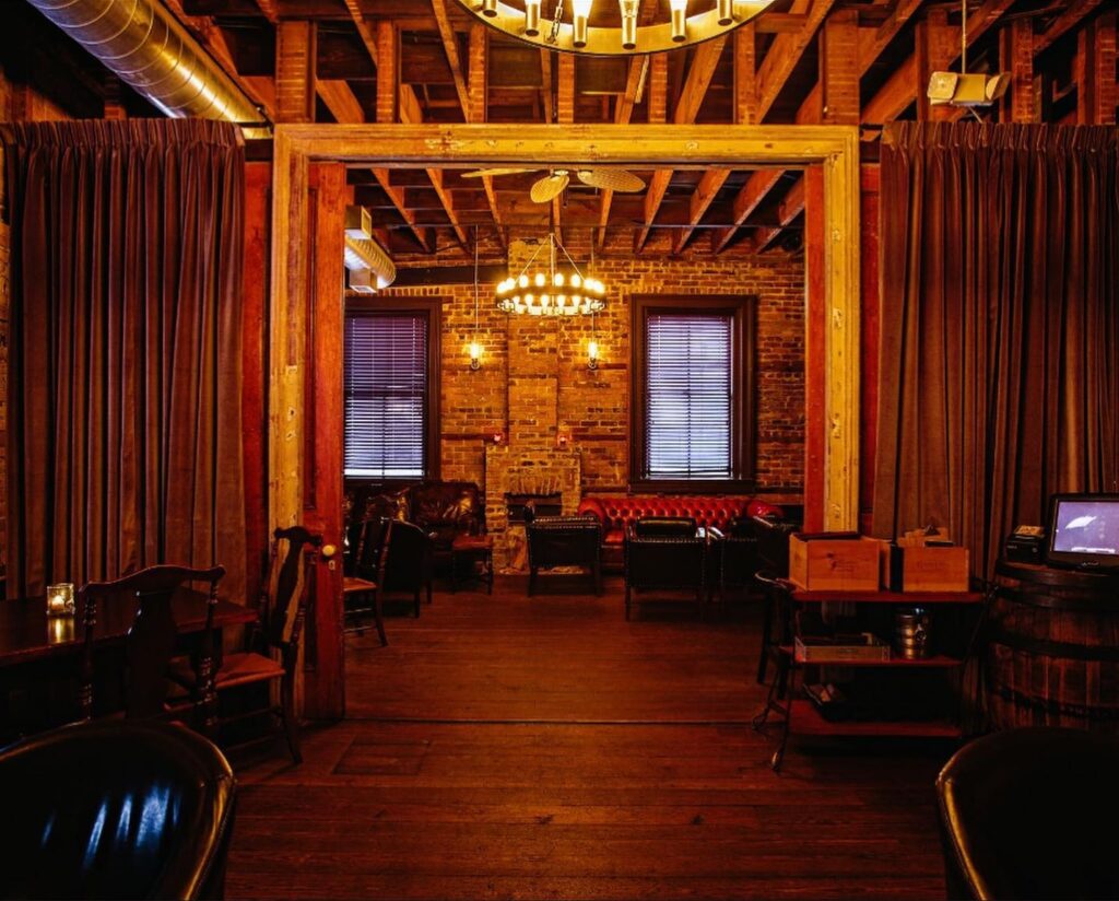 speakeasy-style bar with cozy lighting, exposed brick walls and ceiling