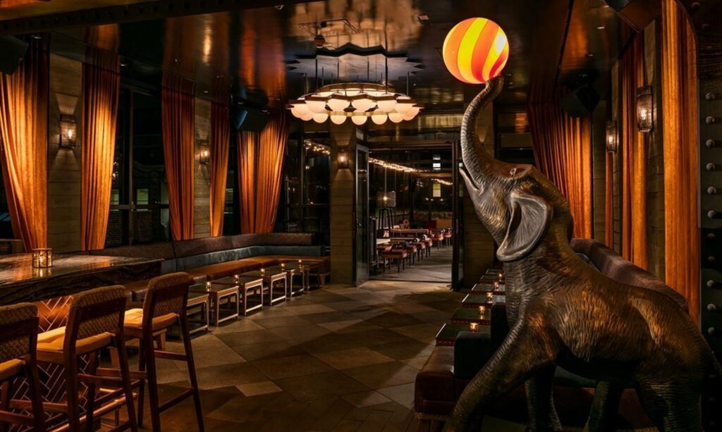Elephant statue with red and yellow ball in front of a modern bar and lounge
