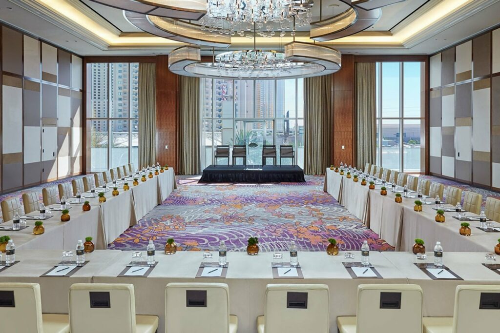 A well-lit ballroom space with floor-to-ceiling windows and an overlooking view of the city