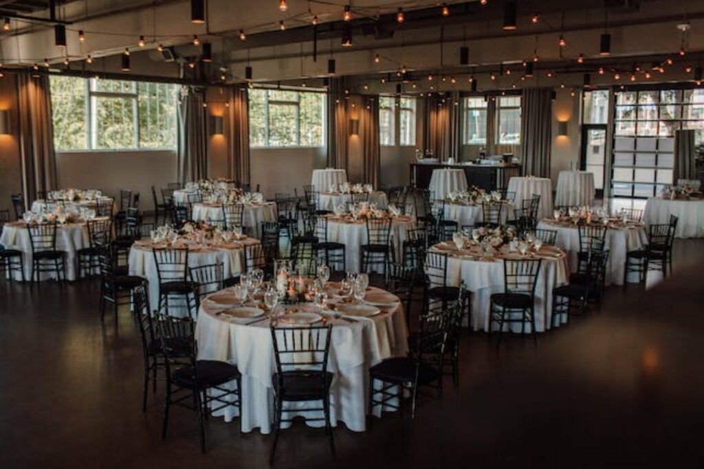 A ballroom with elegantly styles banquet tables, plenty of windows and light fixtures