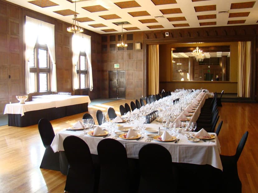 An event space with large windows for natural lighting, long table in the middle and wooden designed floors 