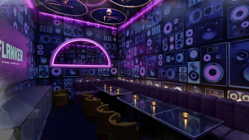 Dark karaoke room with speakers on the walls and purple neon lighting