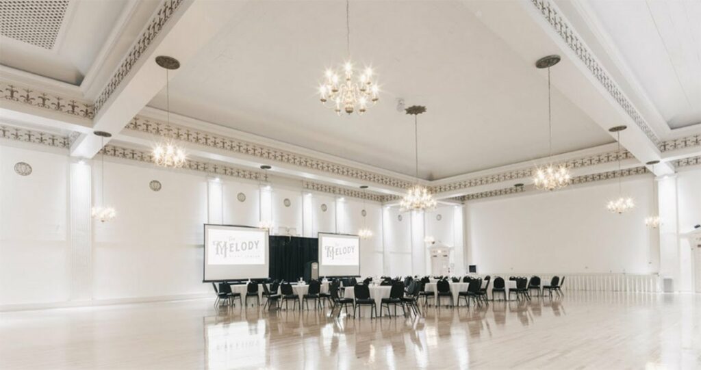A Ballroom with 30-foot high ceiling, ivory and gold tones, brass chandeliers and an expansive hardwood floor 