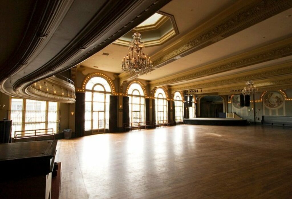 An empty ballroom with giant chandeliers, floor to ceiling windows and a vaulted ceiling