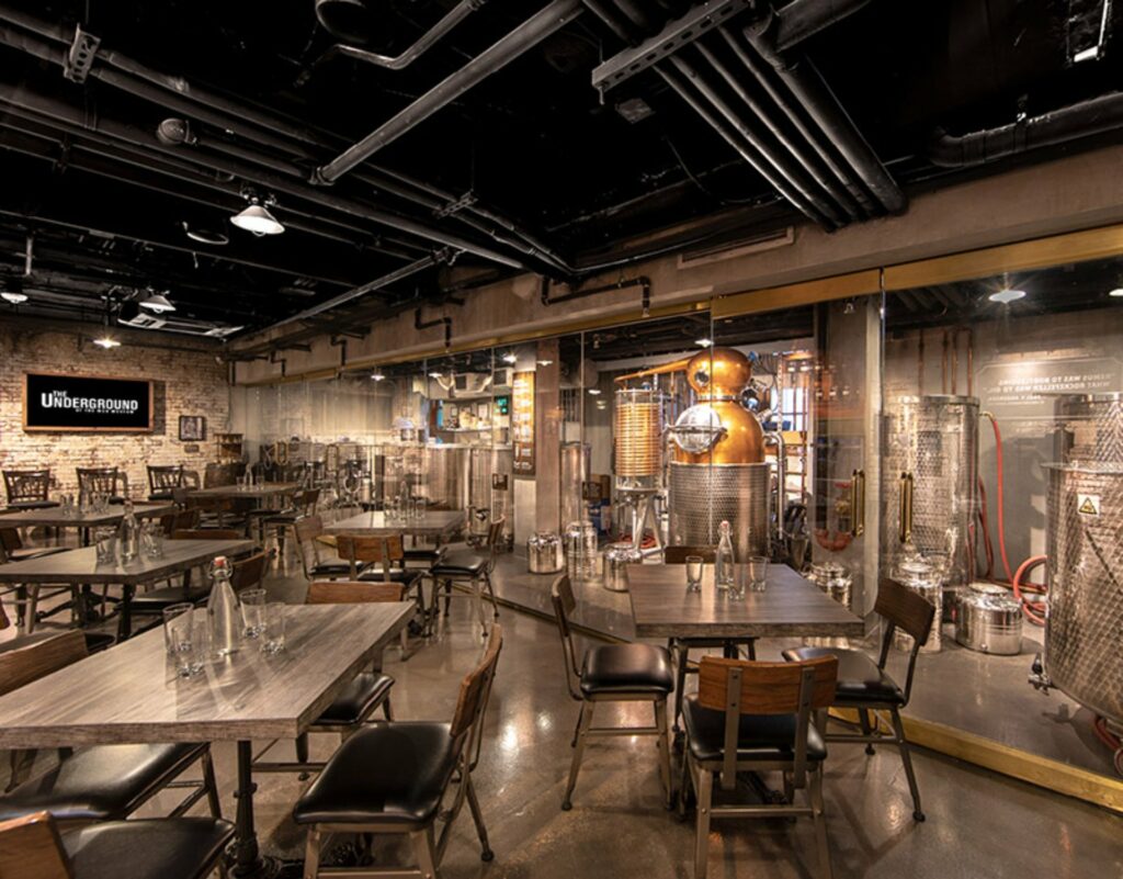 A cozy dining space with exposed ceiling and brewing tanks 
