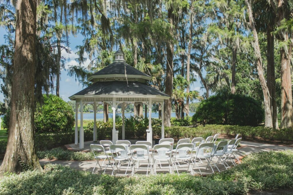 An outdoor event space with gazebo, tall trees and an overlooking view of the lake 