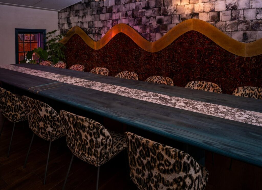 A private dining room with long table and comfy chairs with animal printed design