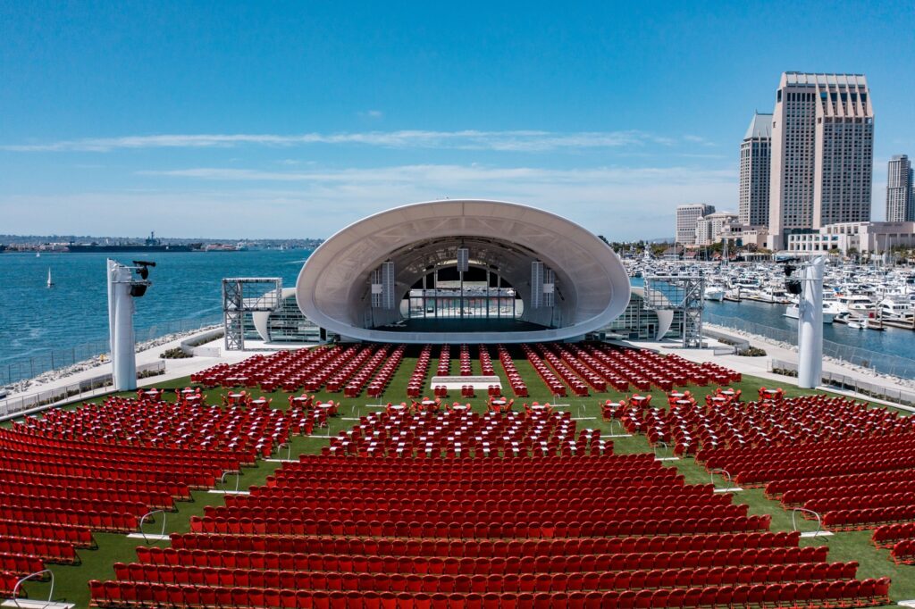 A gigantic outdoor venue with beautiful view of the bay and city. Red chairs are arranged in theatre style. 