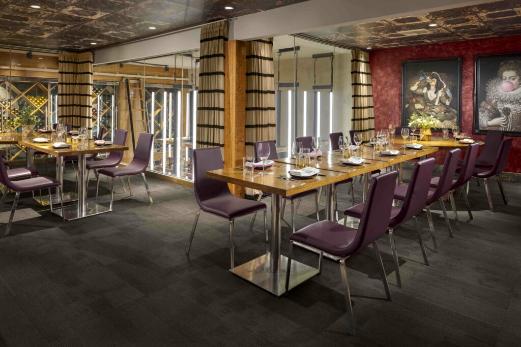 A private dining room with elegant vibe, large wall paintings and a glass window with the view of their wine collections