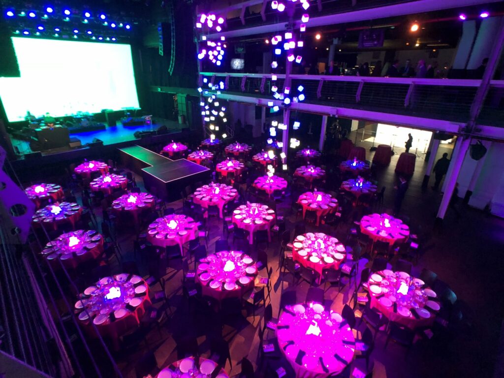 terminal 5 venue with over a dozen round tables and purple uplighting