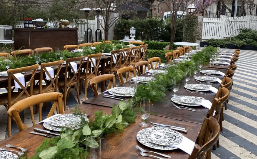 An outdoor space with beautifully arranged long wooden tables and chairs around it. 
