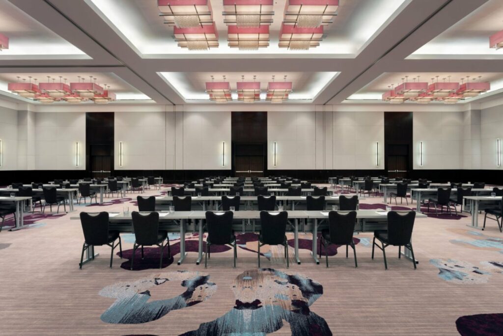 A spacious ballroom with a high ceiling, and plenty of chairs in classroom setup
