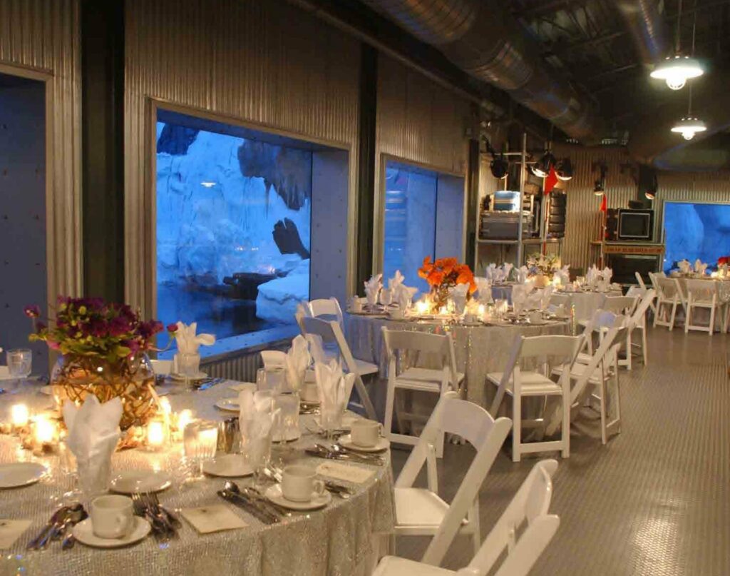 An indoor room with elegantly arranged tables and chairs with Arctic-themed view from one side of the wall. 