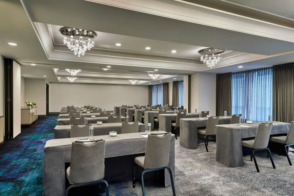 An elegant looking event space with plenty of lighting fixtures and chairs in classroom setup 
