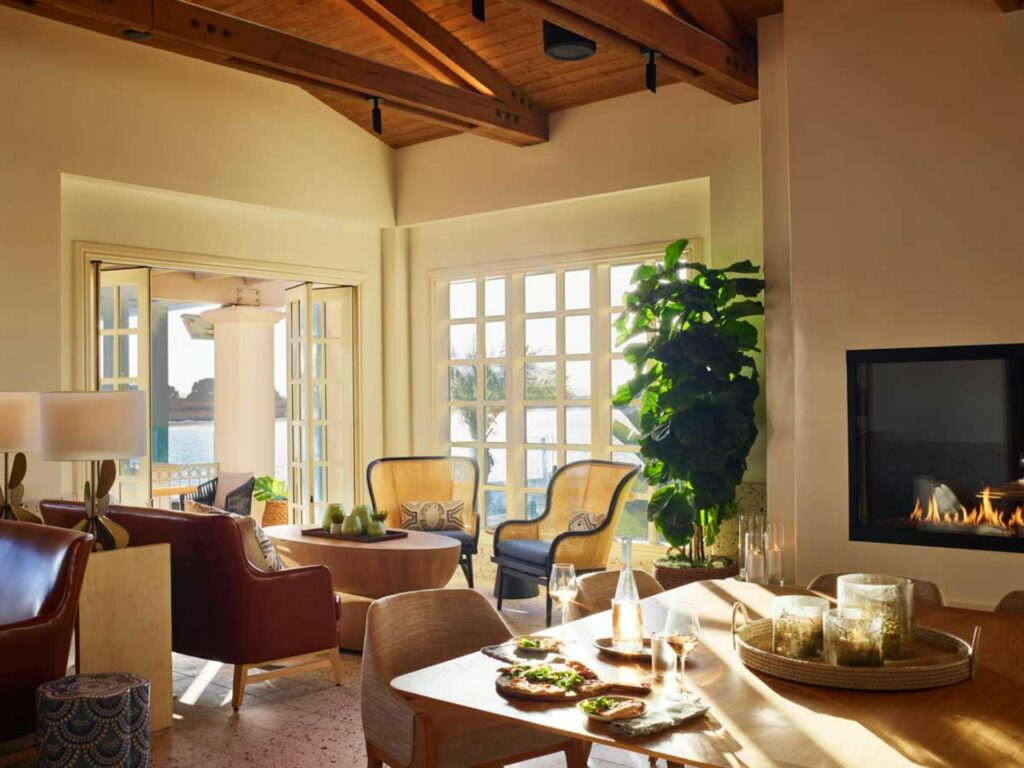 An elegant looking private dining room with a fireplace, large windows and an overlooking view of the Mission Bay.